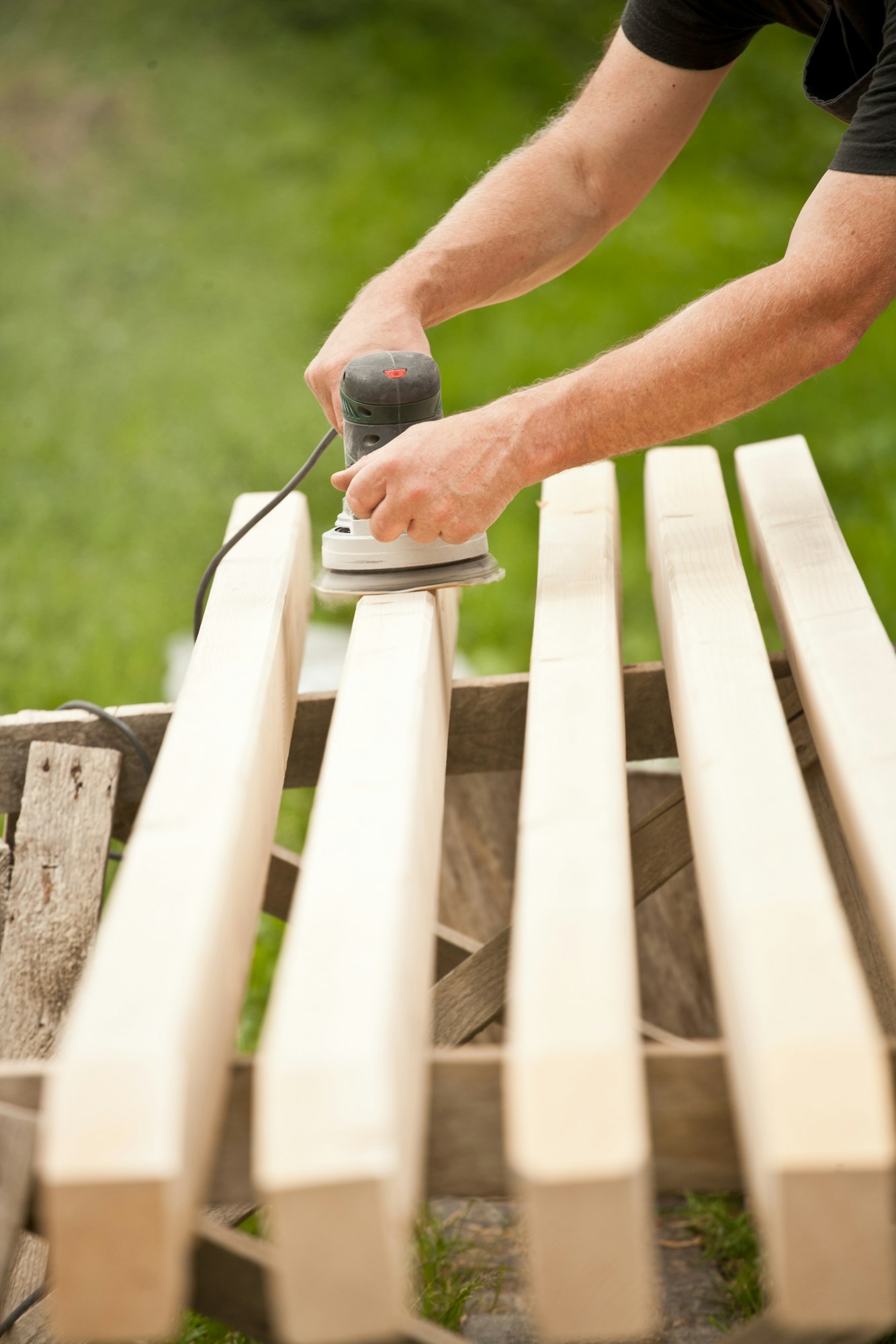 Closeup of a handyman carpenters hand sanding a wood with sander